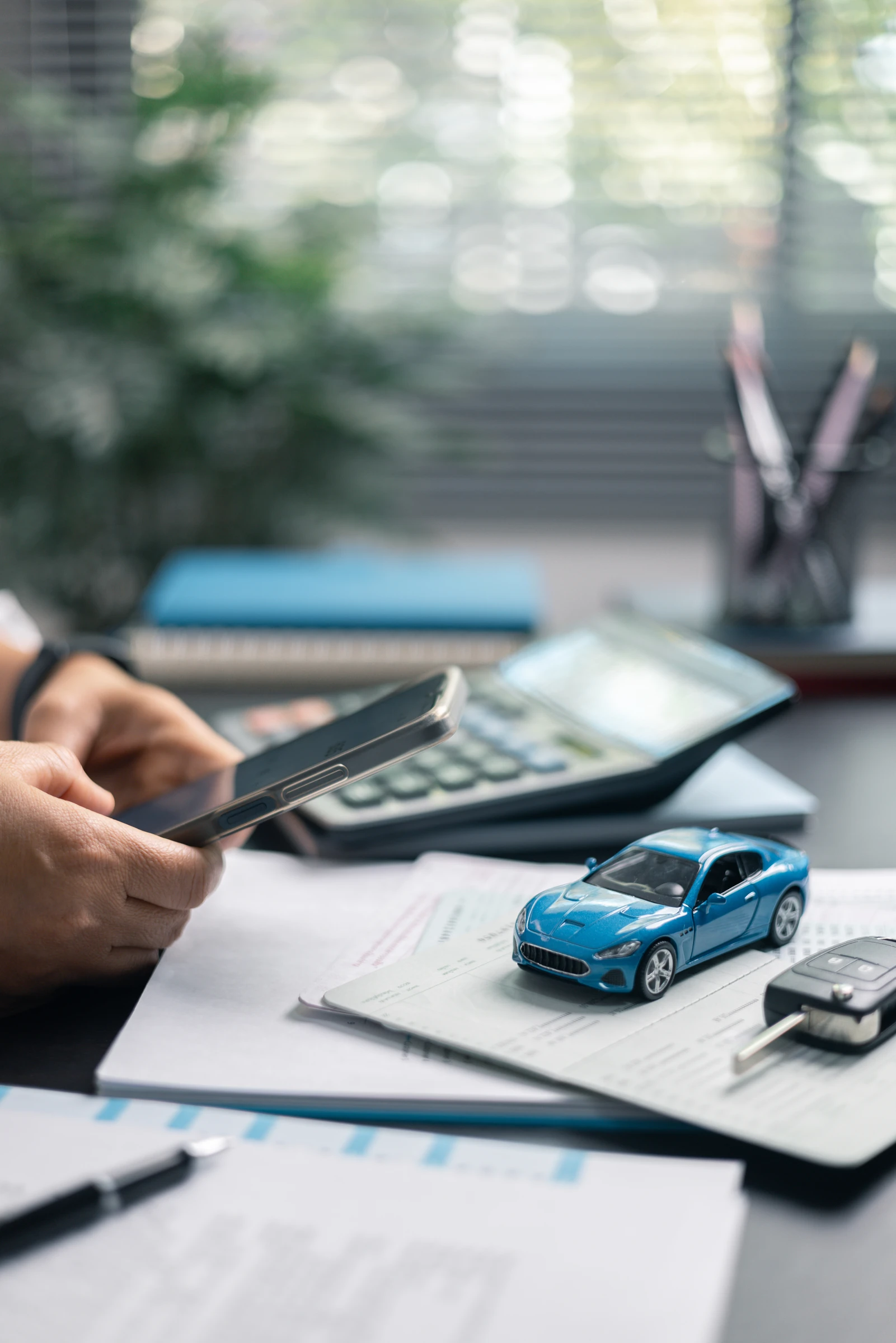 Calculator and model car beside vehicle finance paperwork